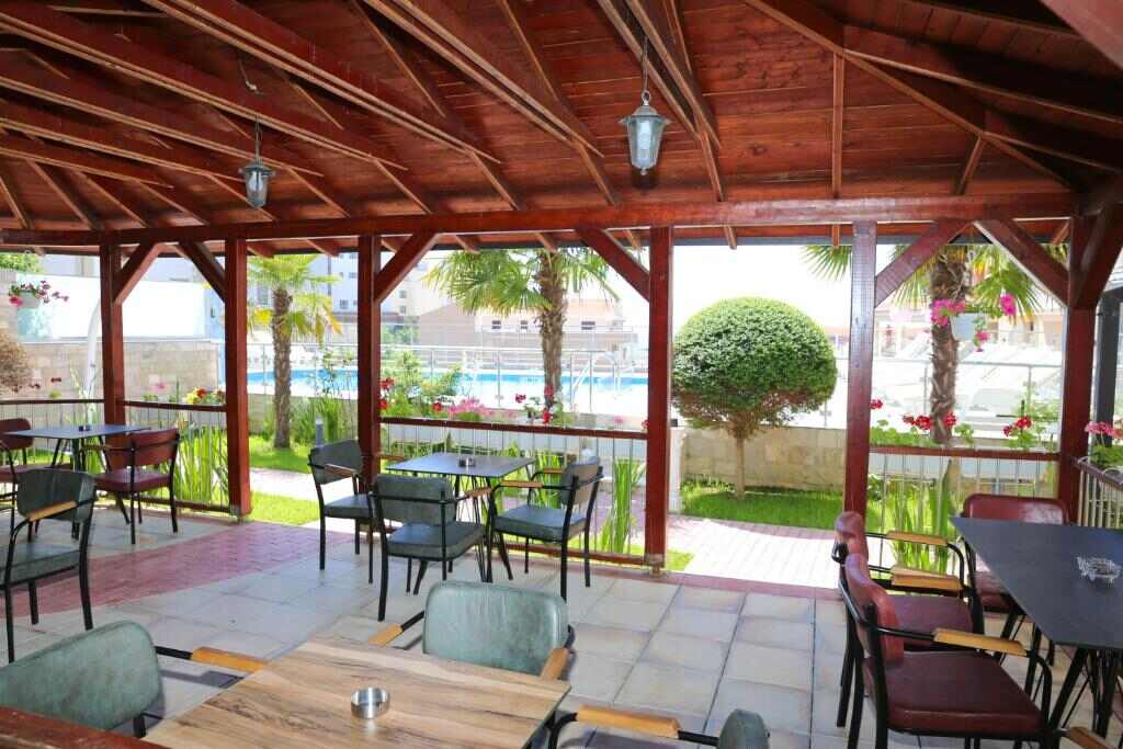 Covered terrace with dining tables beside the pool